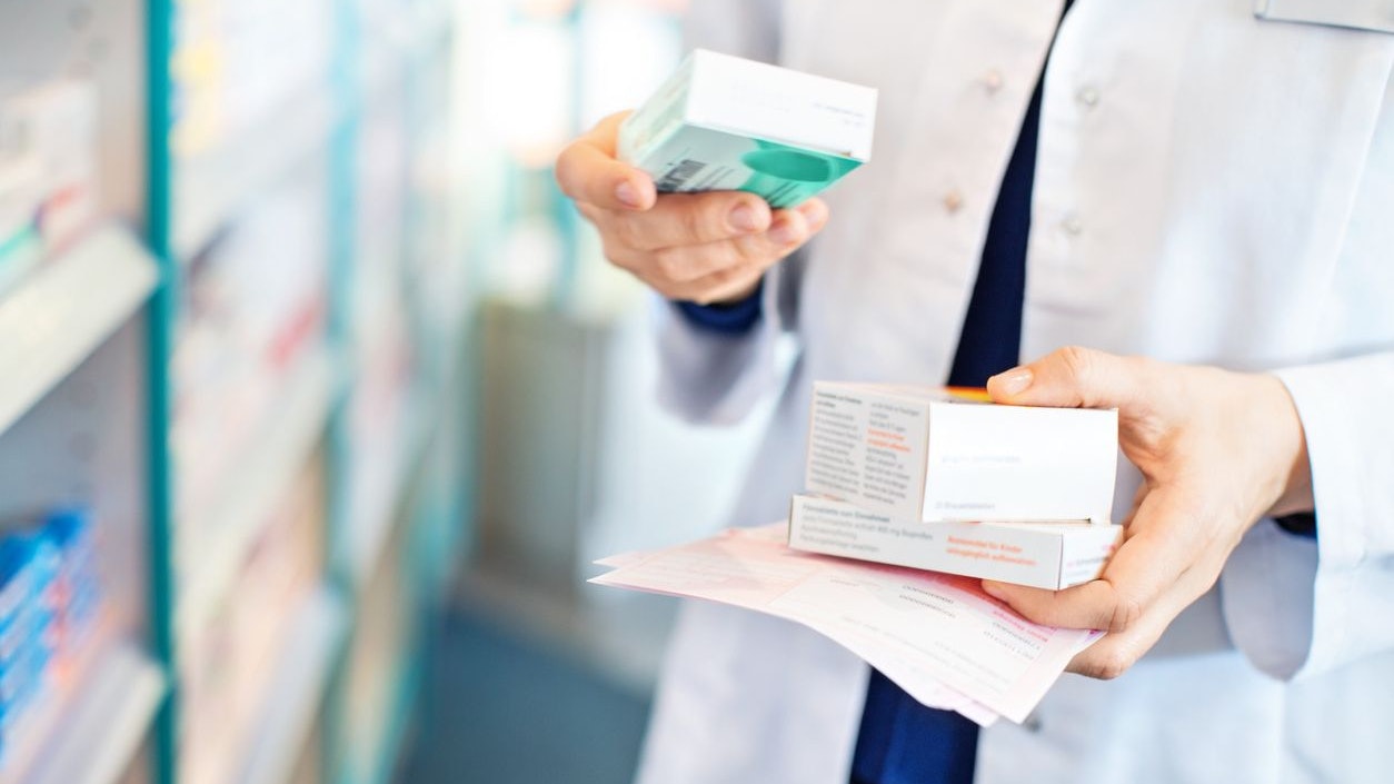 Closeup of pharmacist's hands taking medicines from shelf at the pharmacy