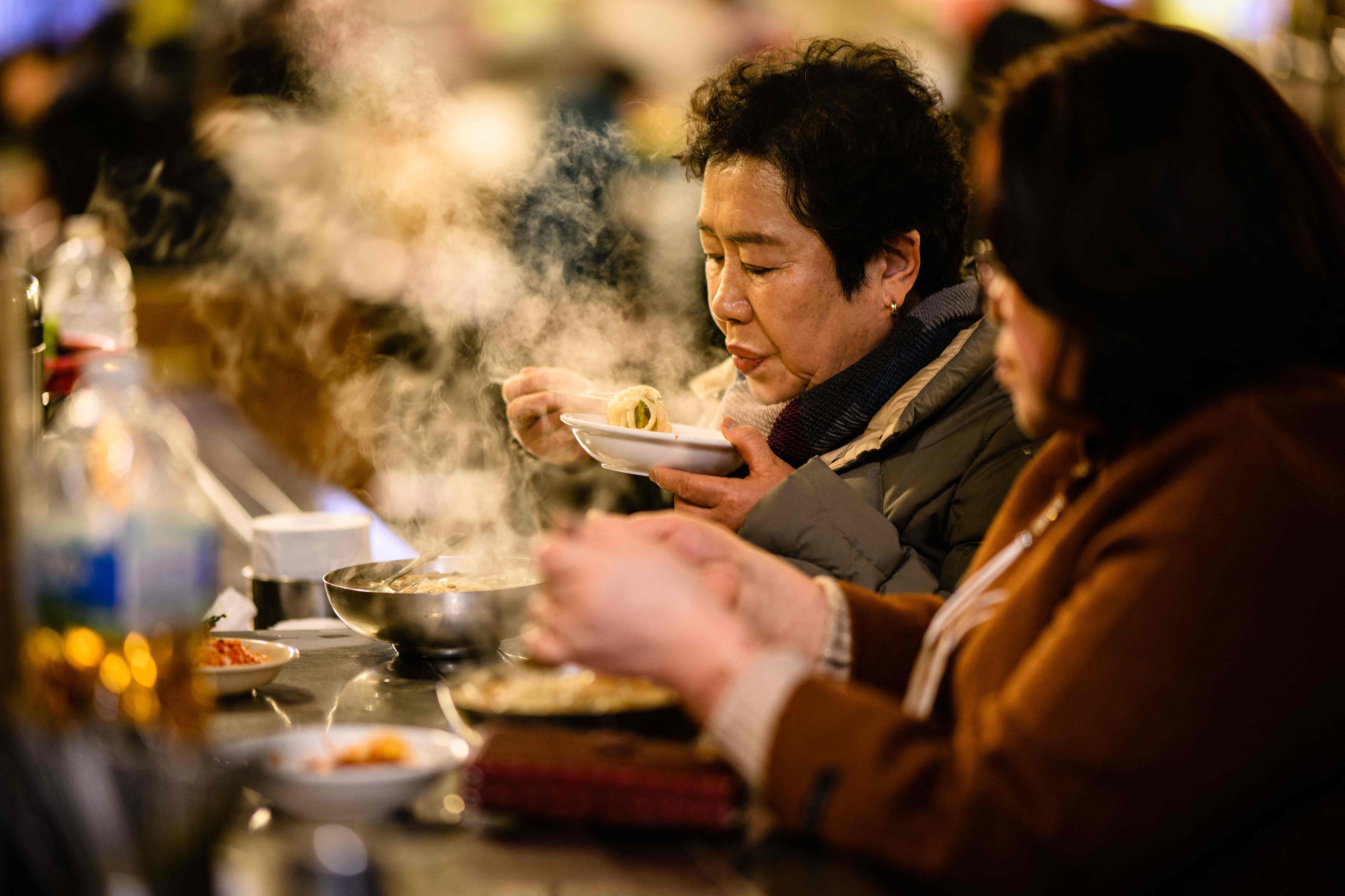 Download von www.picturedesk.com am 29.06.2023 (12:51).  A woman eats a steaming hot bowl of noodles at Namdaemun Market in Seoul on March 13, 2023. (Photo by Anthony WALLACE / AFP) - 20230313_PD6019 - Rechteinfo: Rights Managed (RM) Nur für redaktionelle Nutzung! Werbliche Nutzung erfordert Freigabe: bitte schicken Sie uns eine Anfrage.