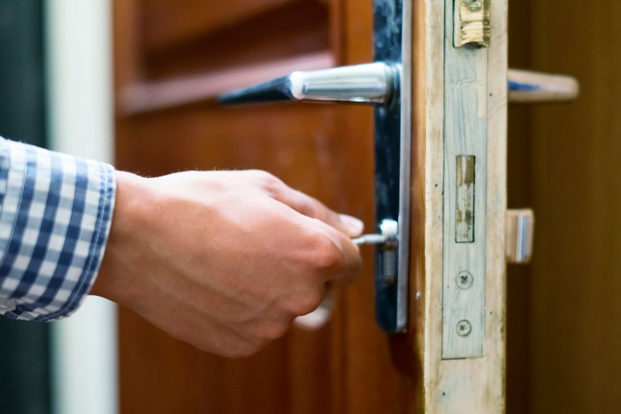close up person hand in checkered shirt opens the door  using keys