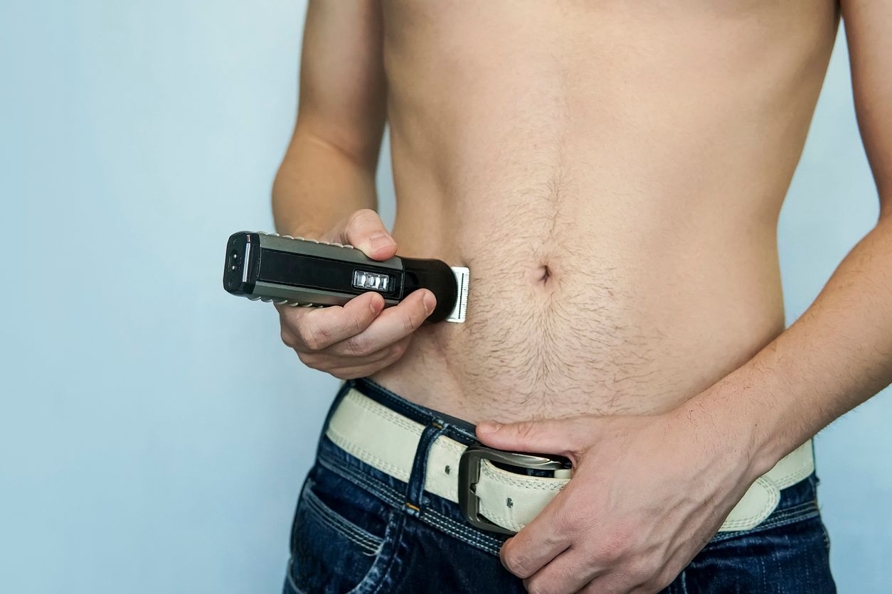 closeup of a young man trimming the hair of his pubis with an electric trimmer. concept of a clean healthy body for men. Man haircut pubic hair with a clipper