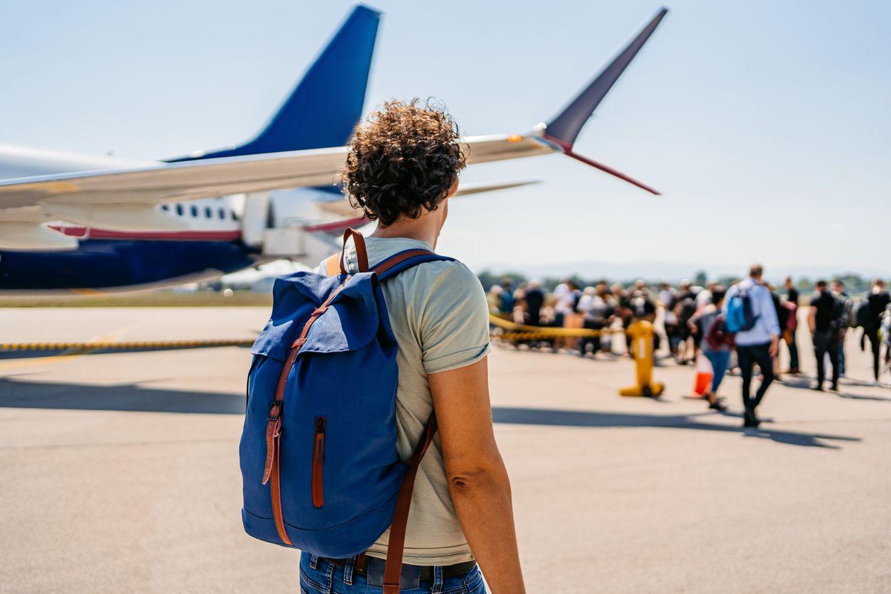 Rear-view of a handsome young man boarding an airplane for vacation.