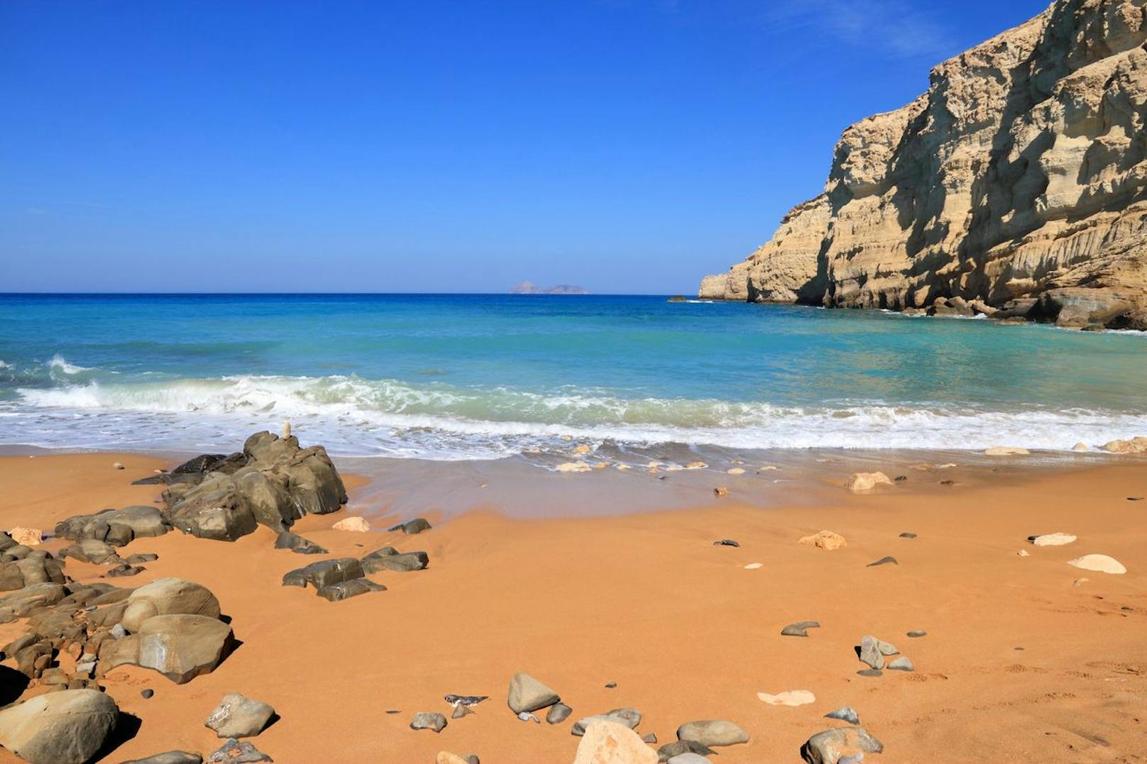 <strong>Red Beach auf Kreta, Griechenland:</strong> Der malerische Strand Kokkinos Ammos, besser bekannt als Red Beach (also roter Strand), liegt 20 Minuten vom Dorf Matala auf Kreta entfernt. Nicht überraschend verdankt der Strand seinen Namen der rot-bräunlichen Farbe – ein optisch atemberaubender Kontrast zum blauen Wasser. Der FKK-Strand ist nur 300 Meter lang und erst nach einem Abstieg zu erreichen. Gutes Schuhwerk, Trinkwasser und Verpflegung sind ein Must, wenn du dich auf den Weg zum versteckten Strand machst.