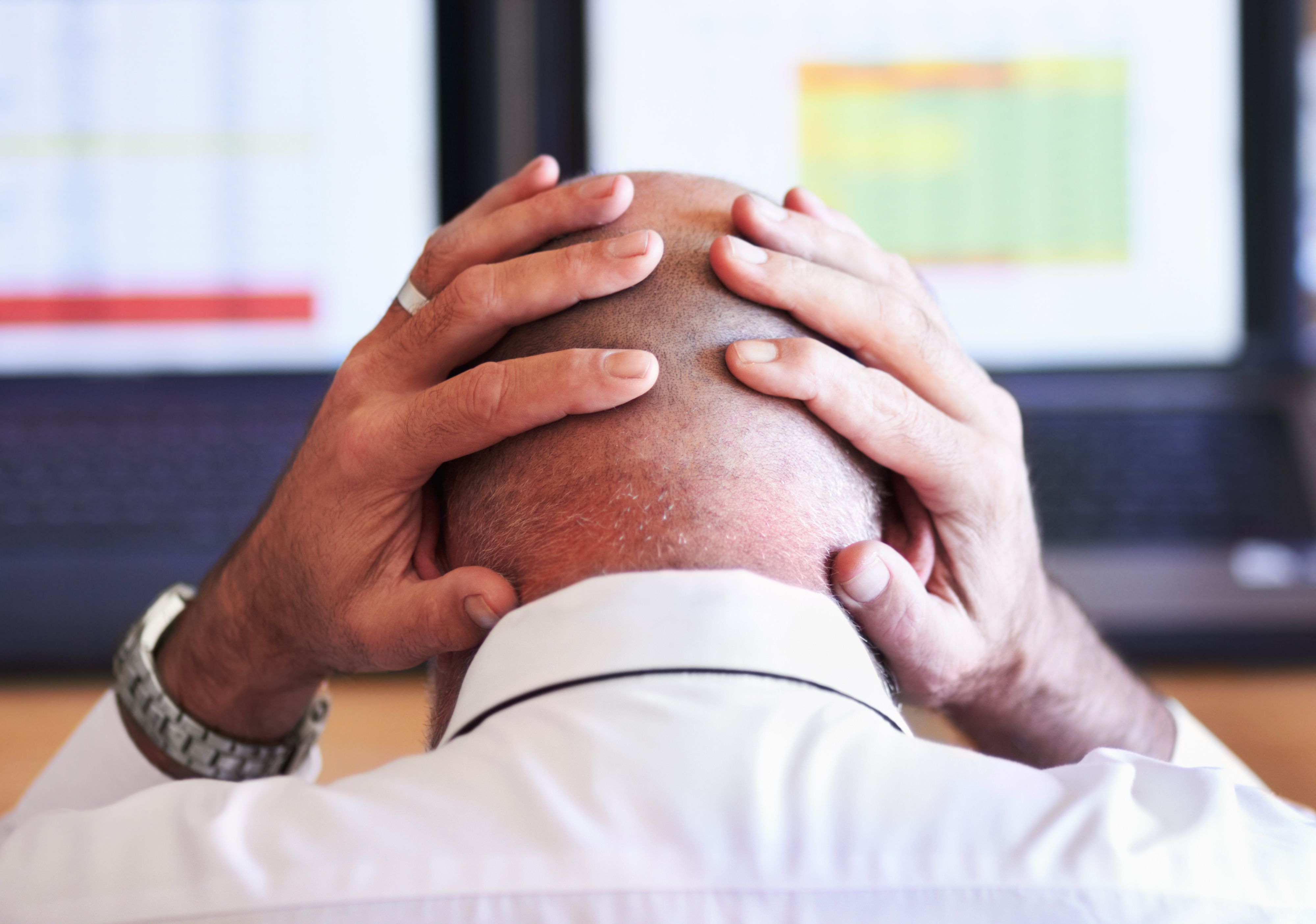 Rear view shot of a businessman looking stressful while placing his hands behind his head