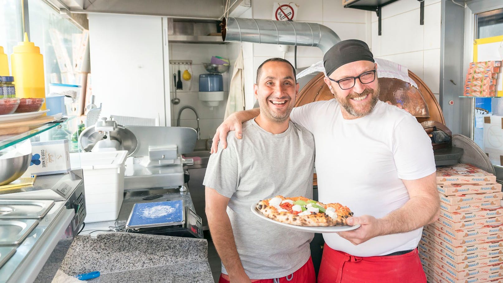 Pizza aus dem Würstlstand: Betreiber Nouri und Pizzabäcker Enzo (v.l.) mit der Büffel-Mozarella Pizza