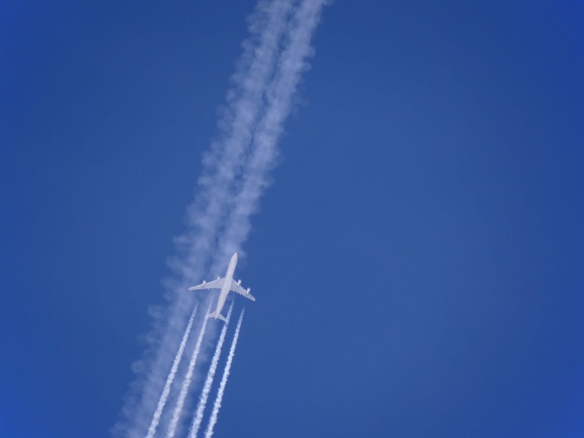 Ein Flugzeug auf Reiseflughöhe samt Kondensstreifen.