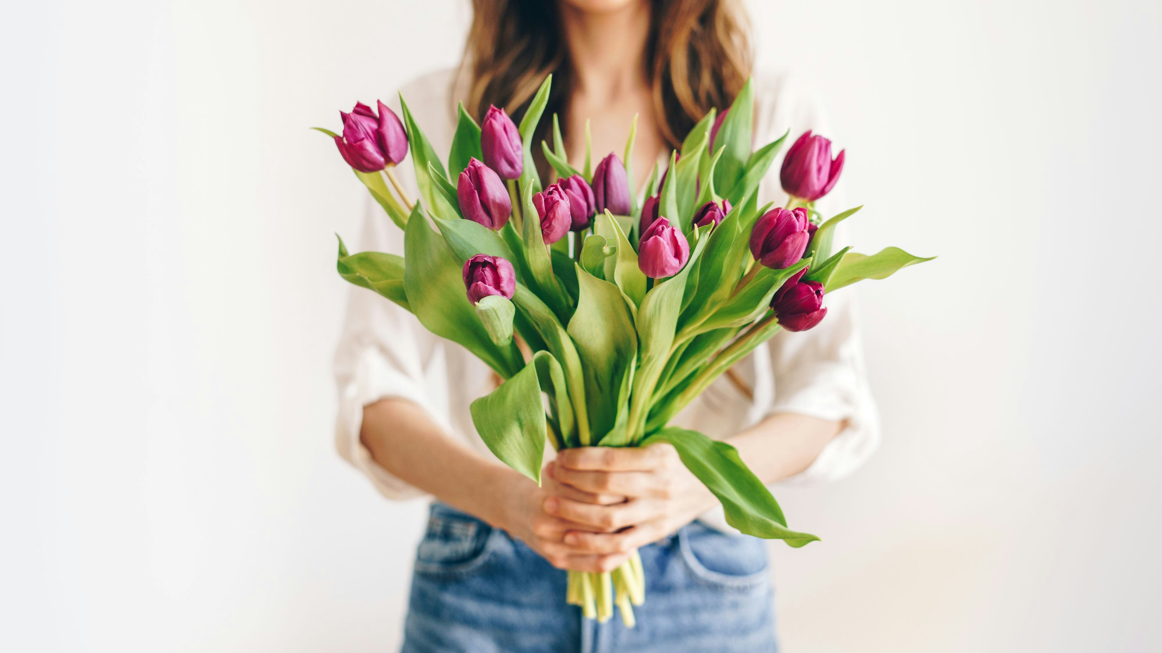 Unrecognizable woman holding a bunch of purple tulips