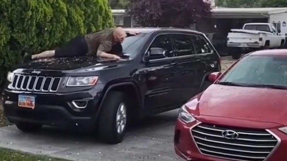 Einem Mann nutzte seinen eigenen Leib, um seinen SUV vor Hagelschäden zu schützen.