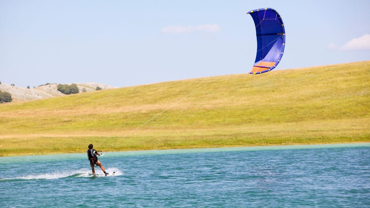 young woman kitesurfer riding in greenish blue lake