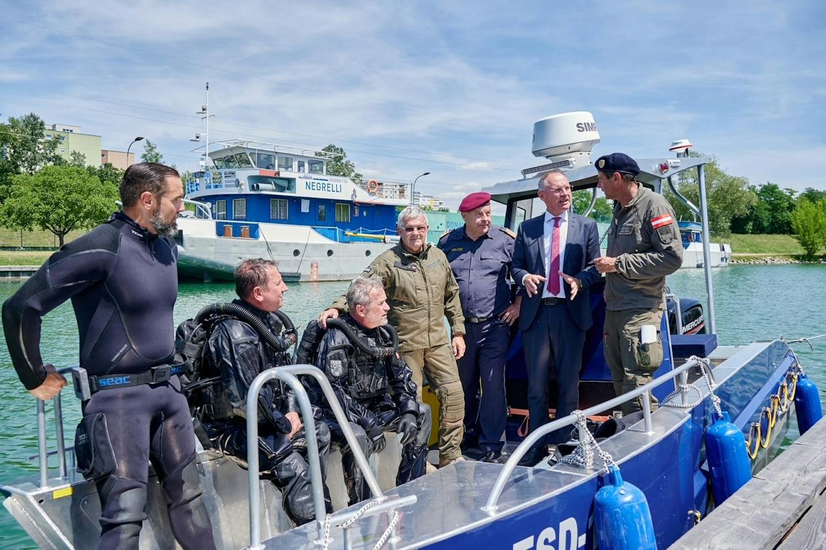 Innenminister Gerhard Karner und DSE-Direktor Bernhard Treibenreif mit Spezialisten und Tauchern des Entschärfungsdienstes im Rahmen einer Übung im Kremser Behördenhafen.