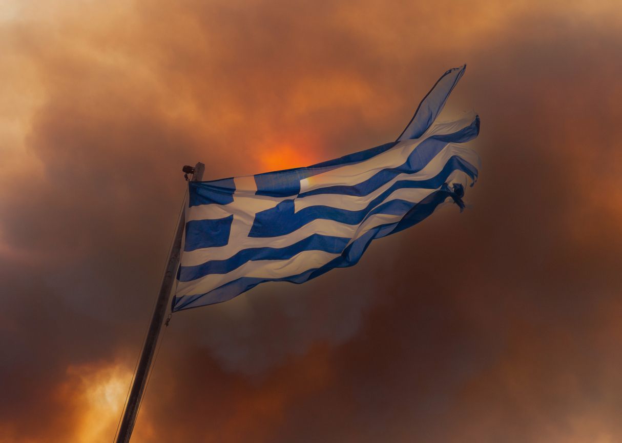Greek flag on the background of smoke from fires in Greece