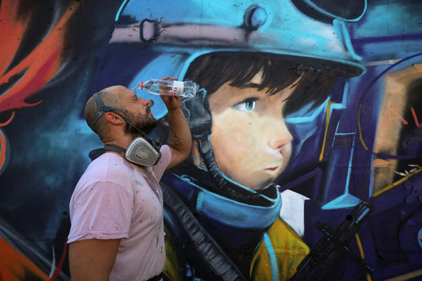 Davide Pianta, ein Graffiti-Künstler aus Italien, erfrischt sich vor seinem Kunstwerk.