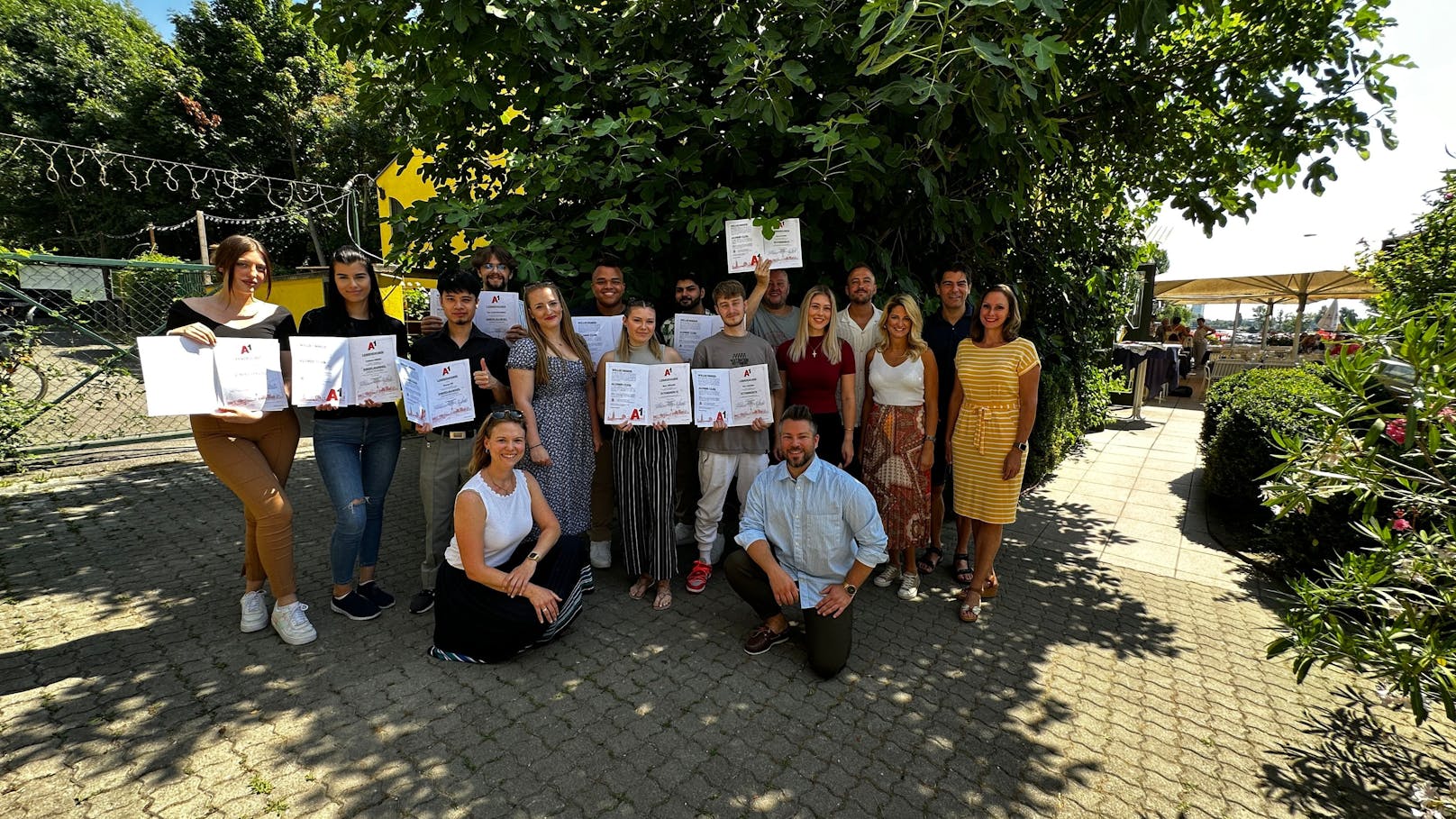 Gruppenbild mit Zeugnissen: Die stolzen Absolvent:innen mit ihren Lernbegleiter:innen.