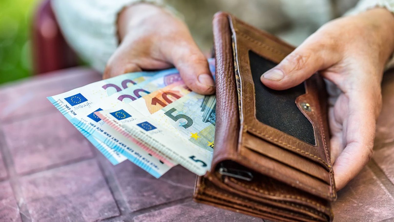 Pensioner woman holding in hands wallet with money.