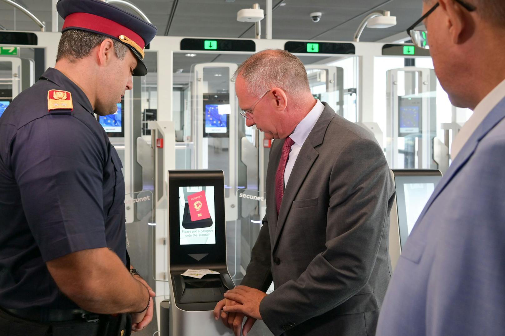 Innenminister Gerhard Karner, der Vorstand der Flughafen Wien AG, Günther Ofner, und der stellvertretende Stadtpolizeikommandant von Schwechat, Florian Grünsteidl, bei der Besichtigung eines E-Gates am Flughafen Wien.