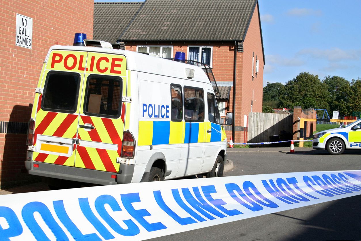 Cordoned crime scene featuring British police vehicles