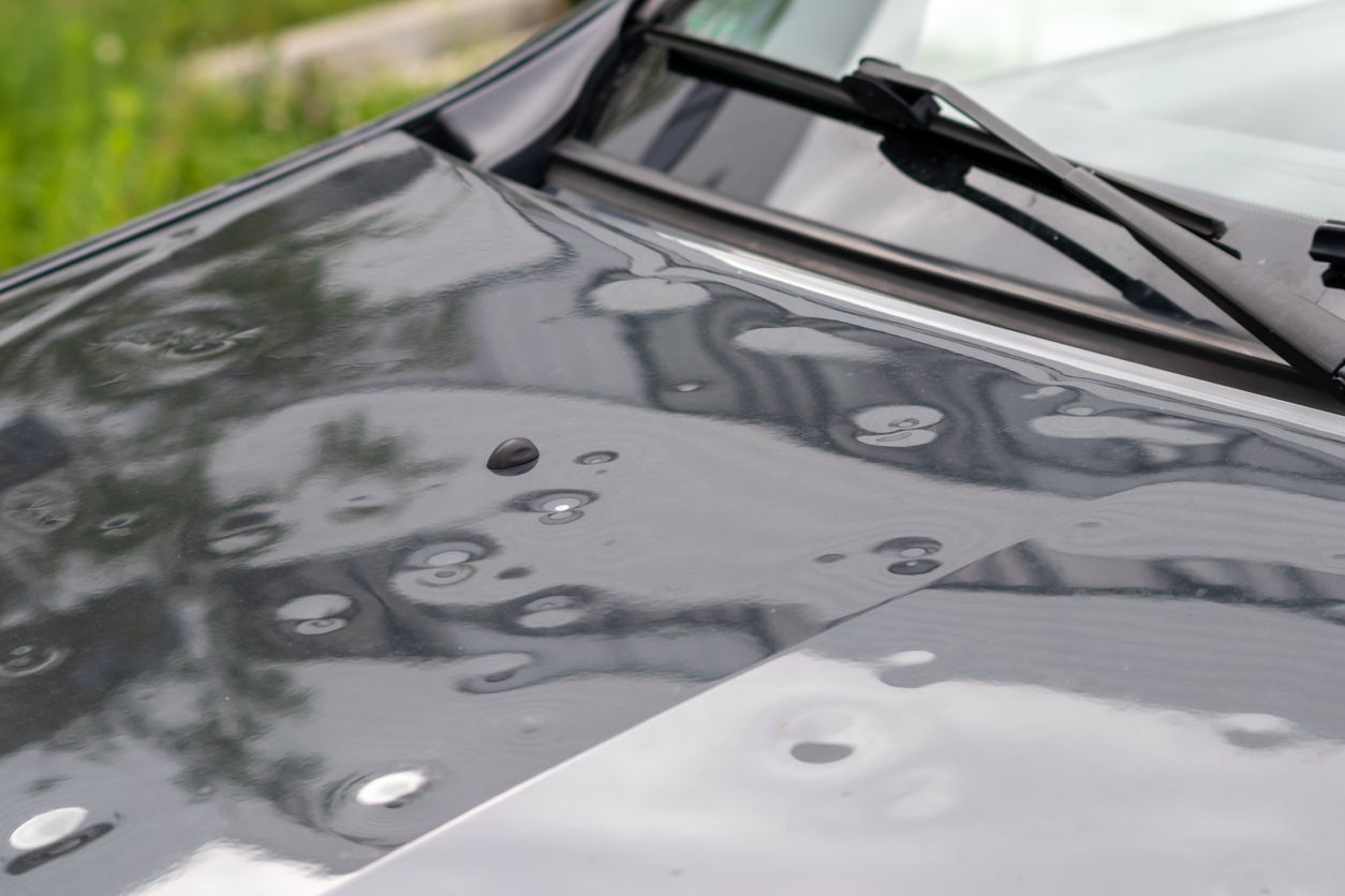 Car engine hood with many hail damage dents show the forces of nature and the importance of car insurance and a replacement value insurance against stormy weather and storm hazards or extreme weather