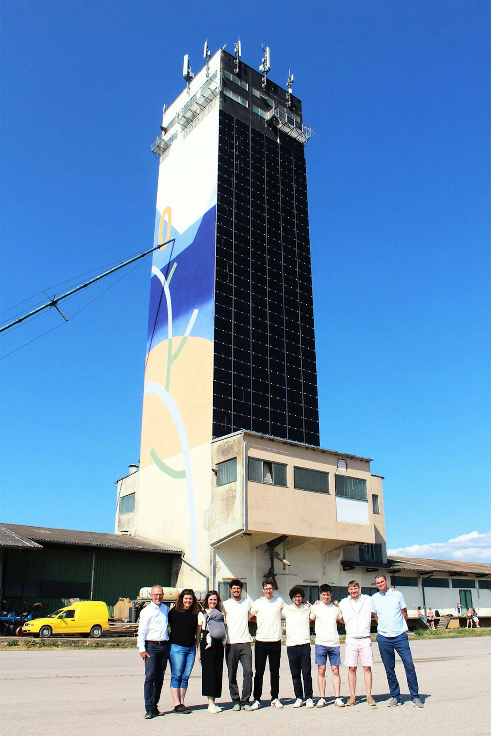 Das Silosophie-Team steht vor dem Siloturm mit Photovoltaikmodulen.