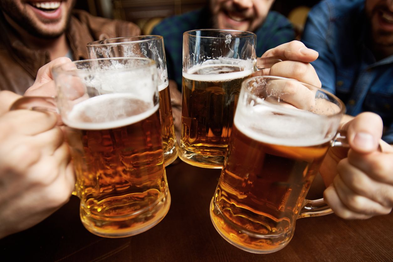 Close-up of male hands clinking beer mugs