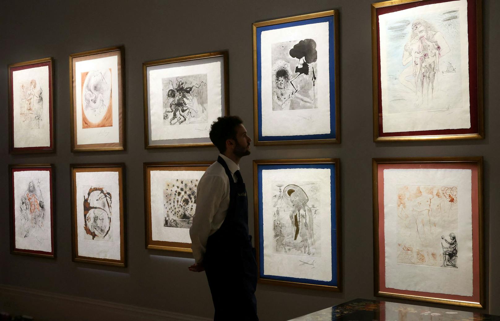 Ein Mitarbeiter von Sotheby's begutachtet eine Reihe von Radierungen von Salvador Dali.
