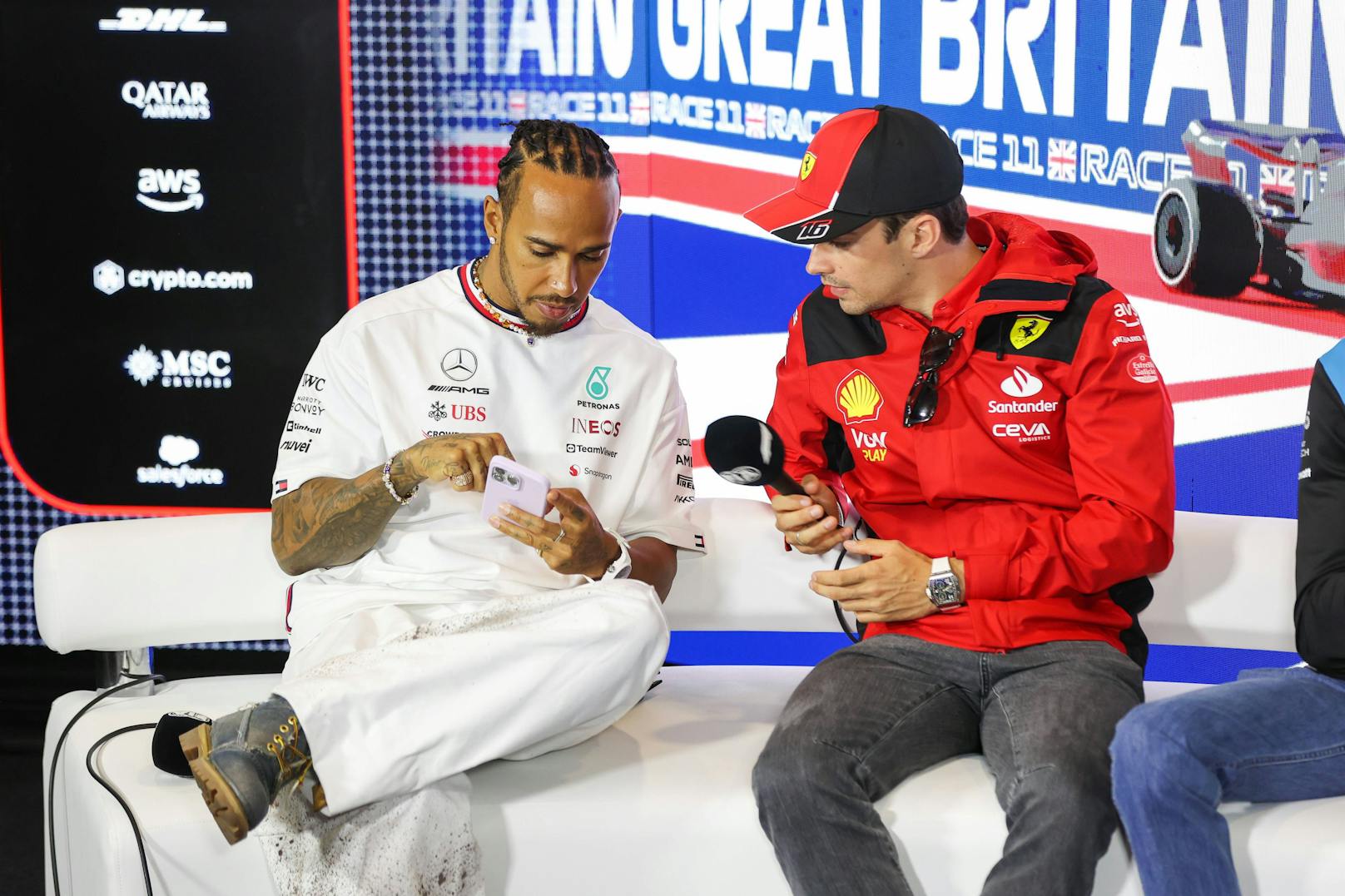 Lewis Hamilton winkt ein Ferrari-Cockpit.