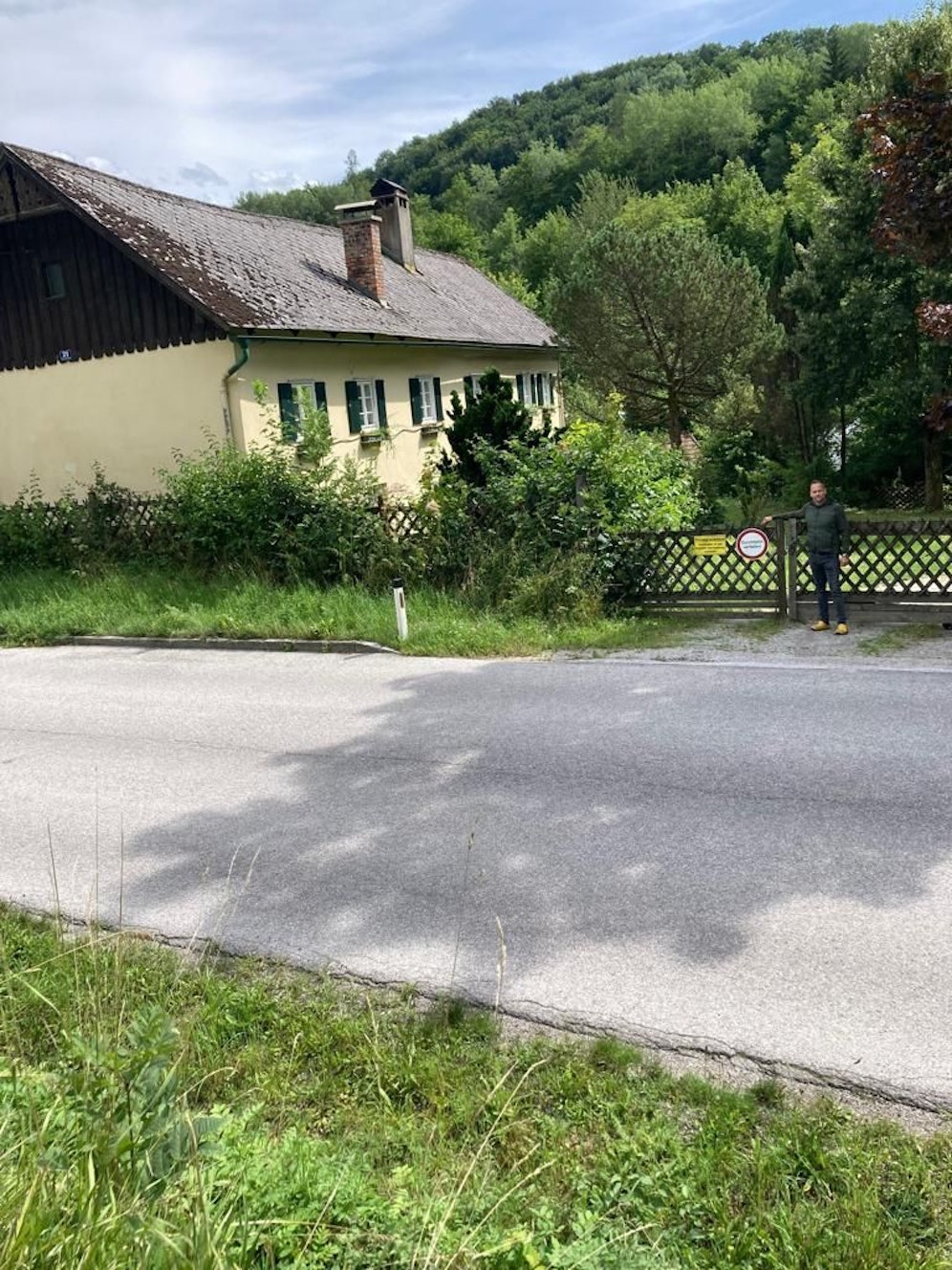 Stefan H. vor dem Weg, der mit einem Tor versperrt ist.