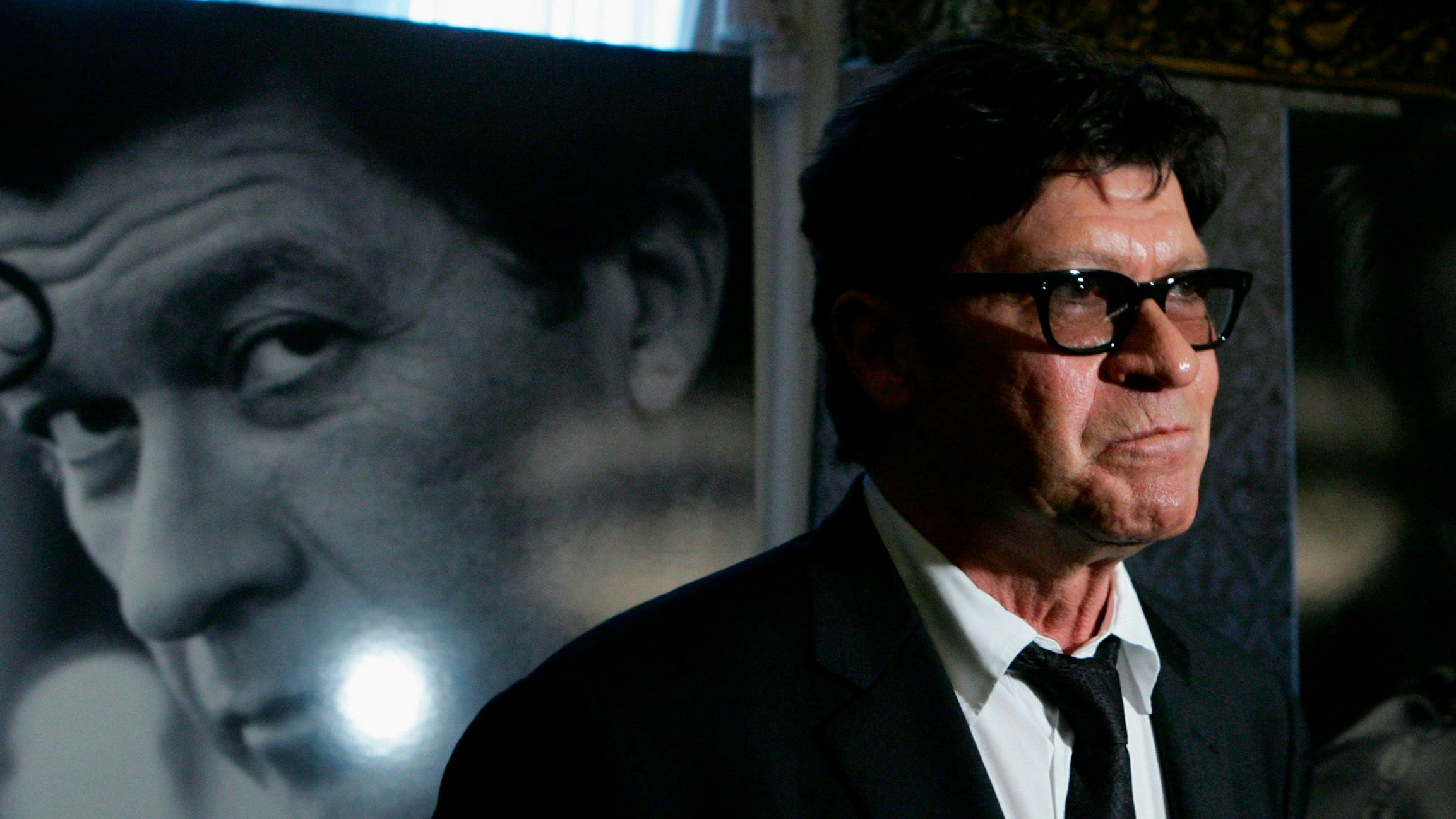 Musician Robbie Robertson, of Canada, pauses while taking part in an interview in front of a poster of himself during a reception on Parliament Hill in Ottawa November 2, 2006. Robertson will receive a Governor General's Performing Arts Award during a ceremony in Ottawa on Friday.        REUTERS/Chris Wattie   (CANADA)