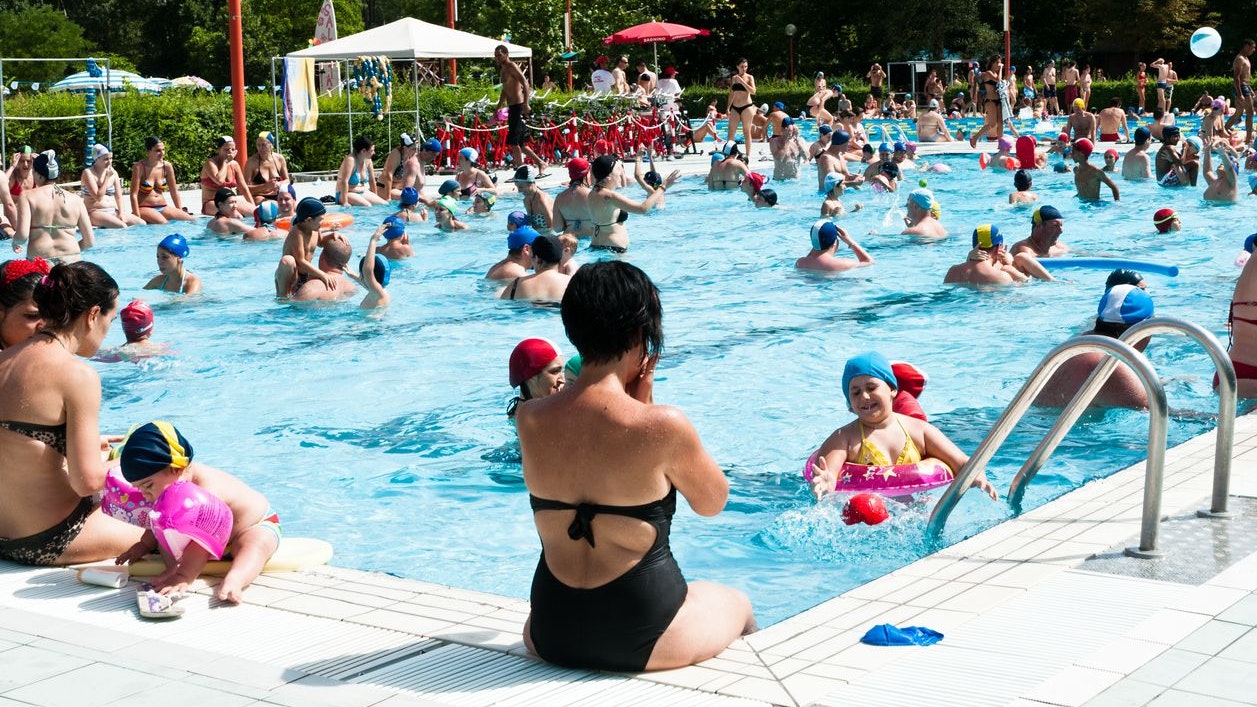 "Bologna, Italy - July 1, 2012: Adulta and families with children refreshing themself and having fun in a crowded swimming pool near Bologna (Italy). It's a sunny day, during a very hot summer."