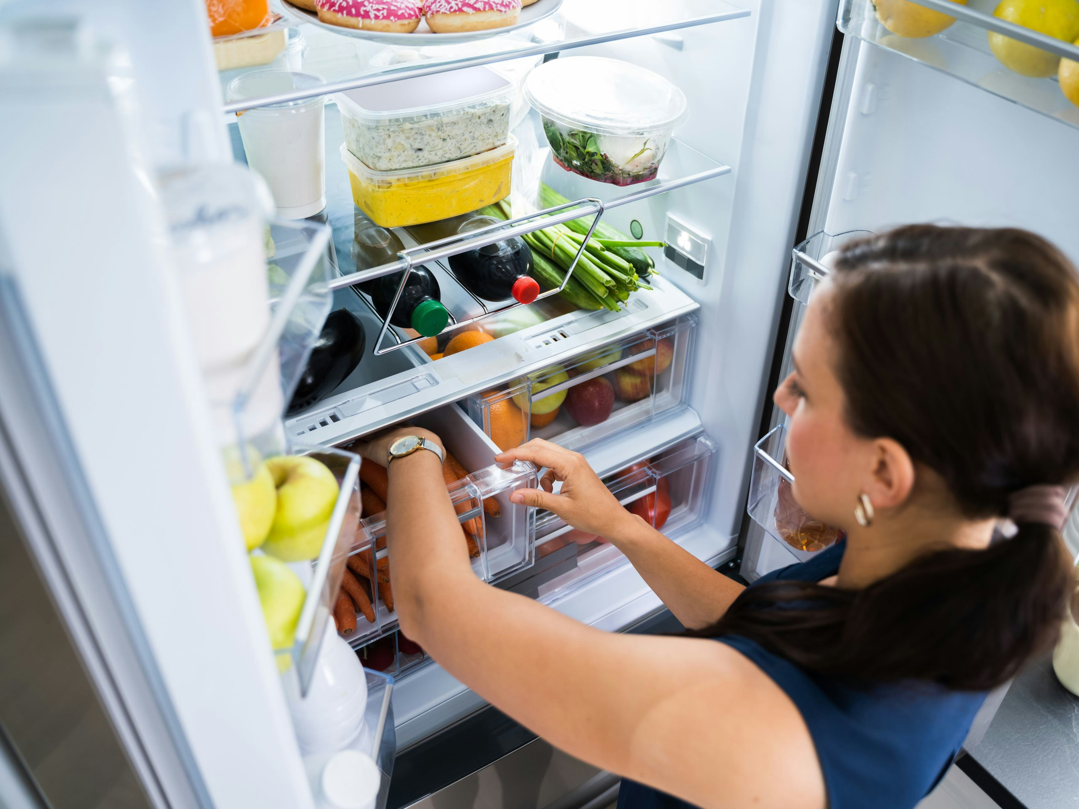 Women Looking For Food Inside Fridge In Kitchen