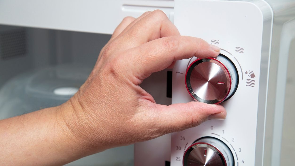 A person uses a microwave oven.We use household appliances at home.