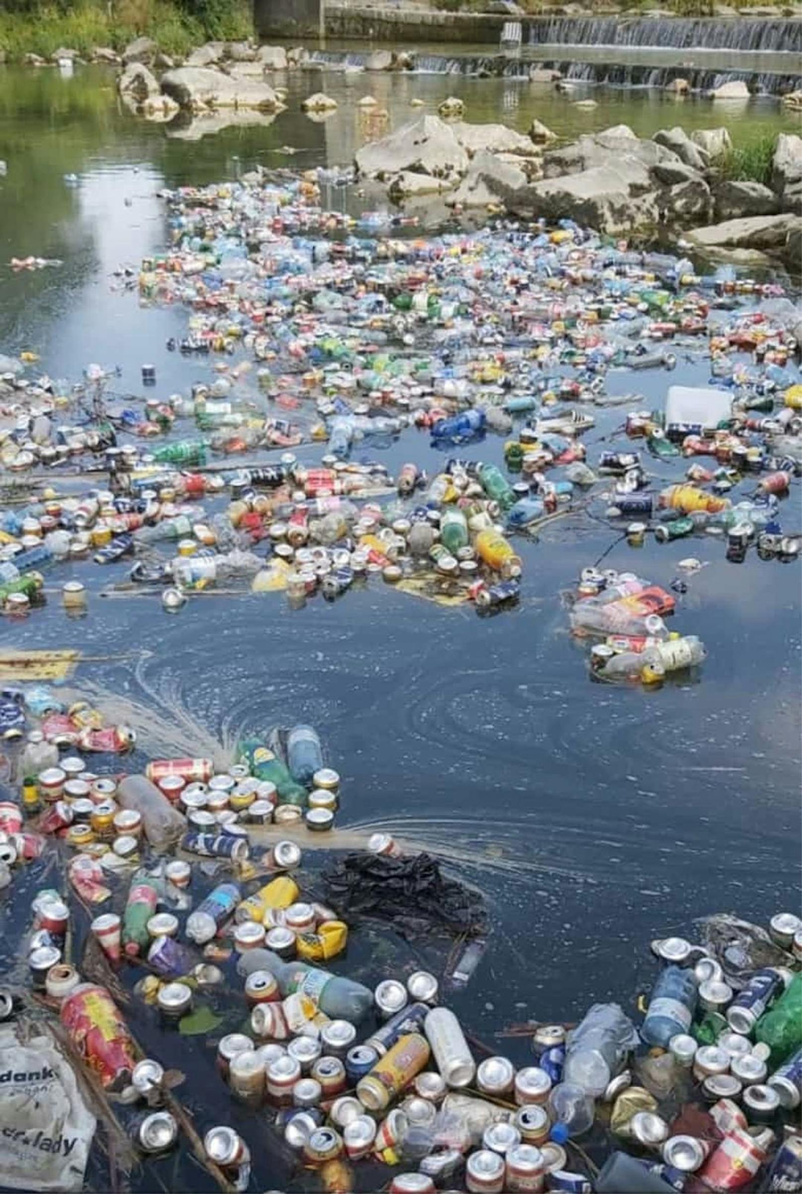 Unzählige Bierdosen und Plastikflaschen schwimmen im Fluss.