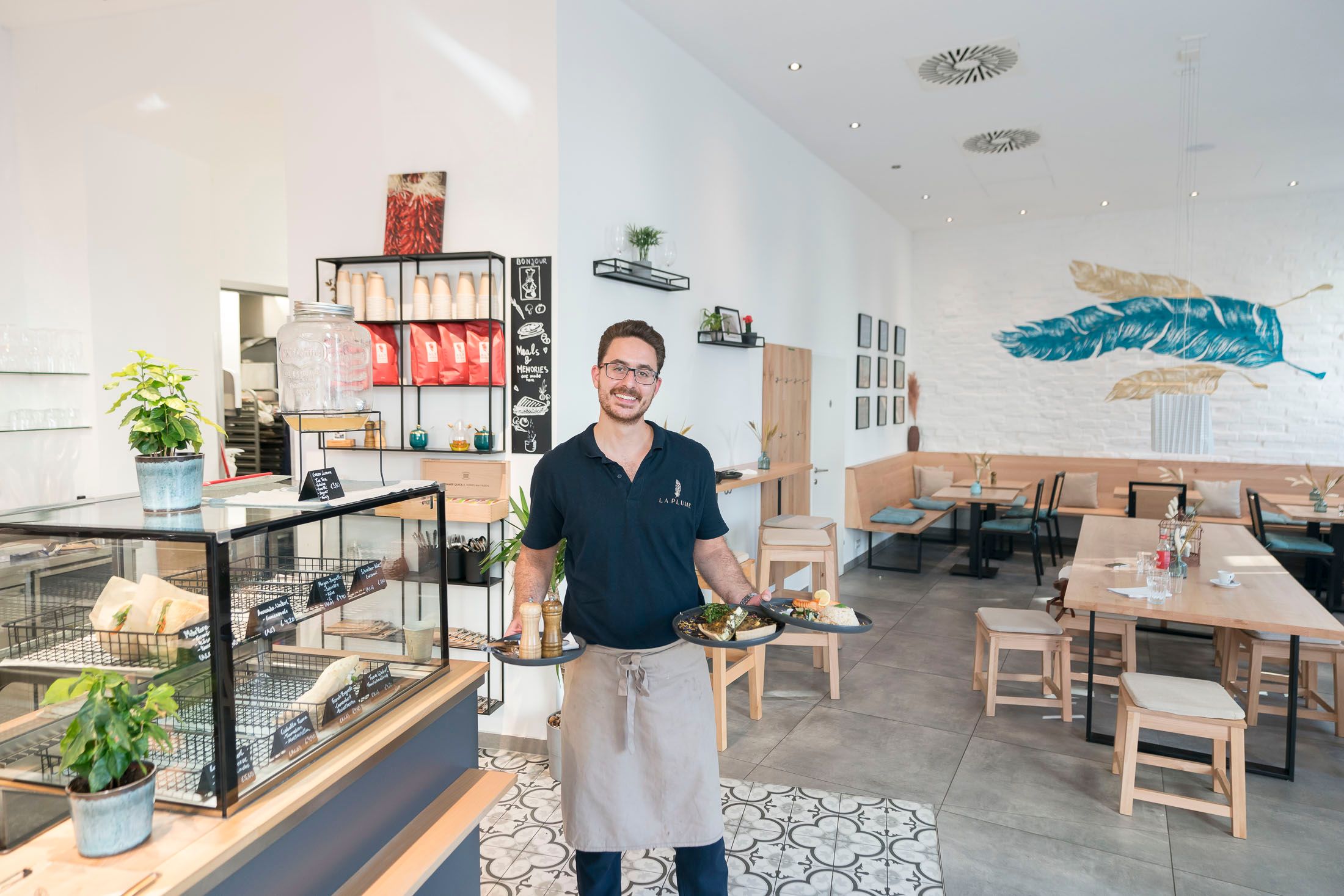 Furkan Kocabay mit dem Bestseller Quiche und einem Mittagsteller Lachs an Reis