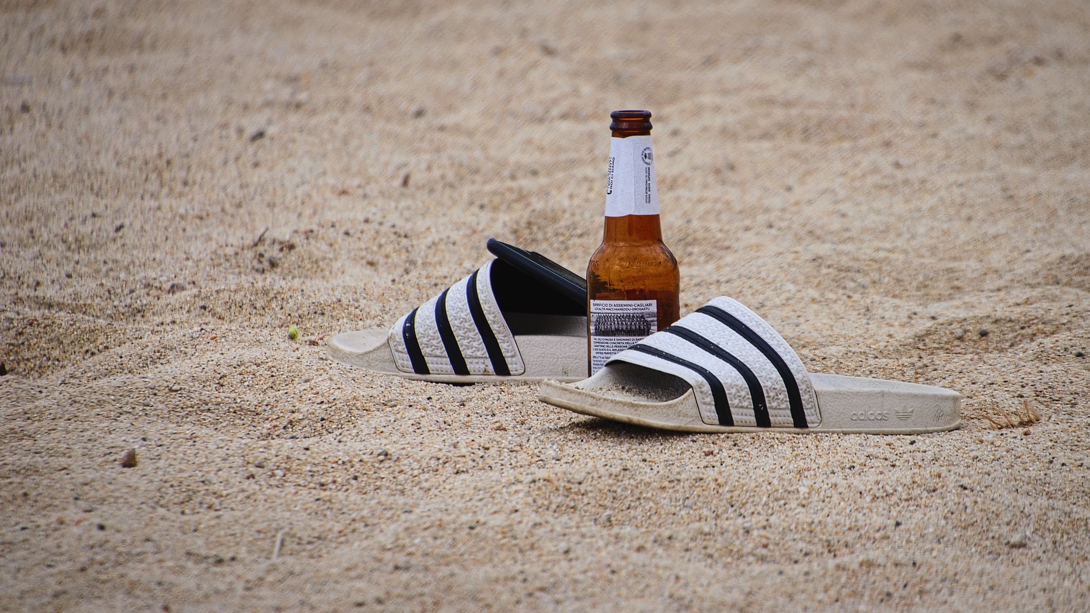 Download von www.picturedesk.com am 28.08.2023 (11:05).  Slippers with a bottle of beer on the sandy beach. (CTK Photo/Petr Malina) - 20220412_PD20041 - Rechteinfo: Rights Managed (RM)