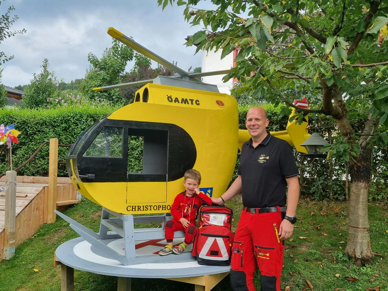 Ganz stolz im eigenen Garten: Papa Roman mit Fabio sowie Rettungshubschrauber und eigenem Helipad.