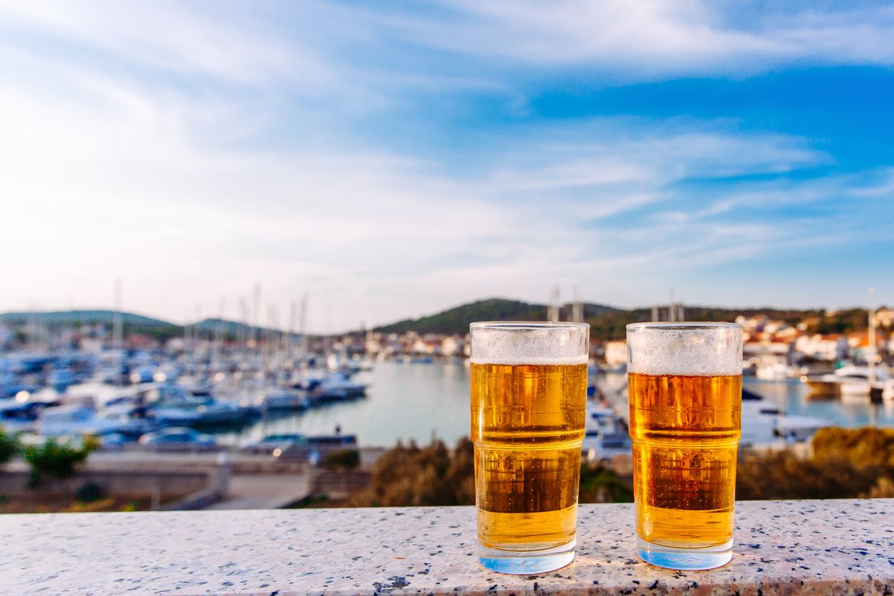 Cold beer and summer day on beach with blurred landscape of sea