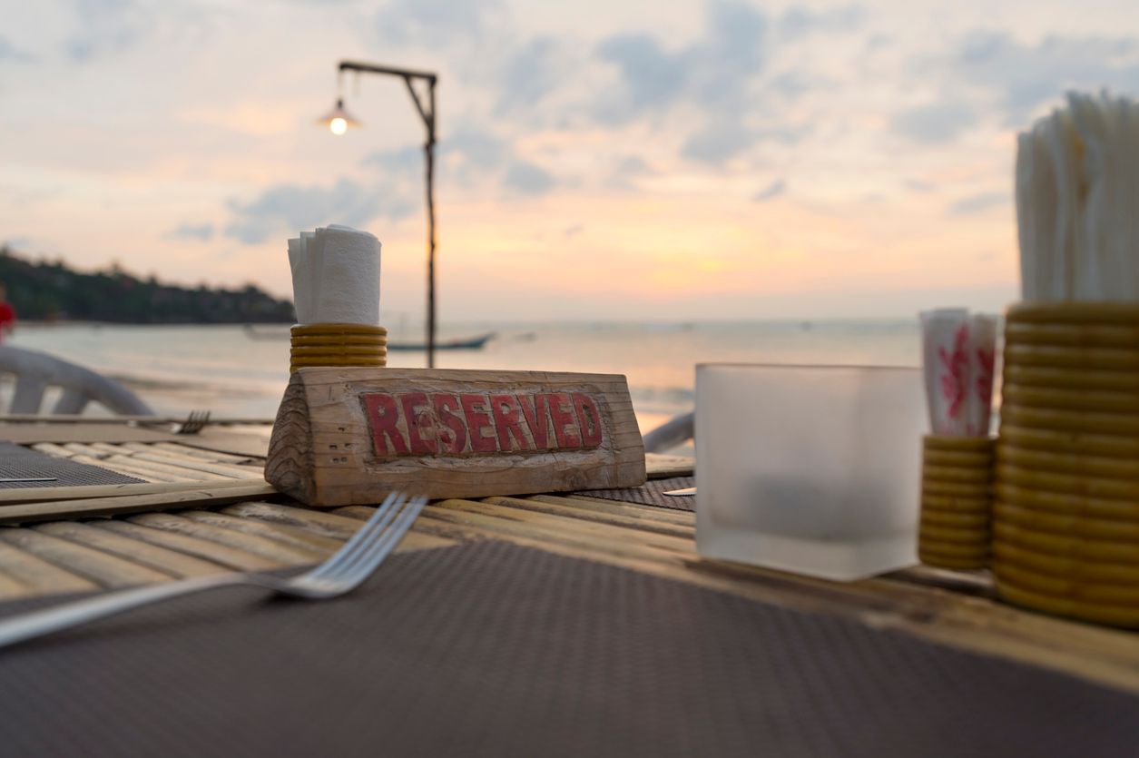Reserved sign on a table at a beach restaurant at sunset