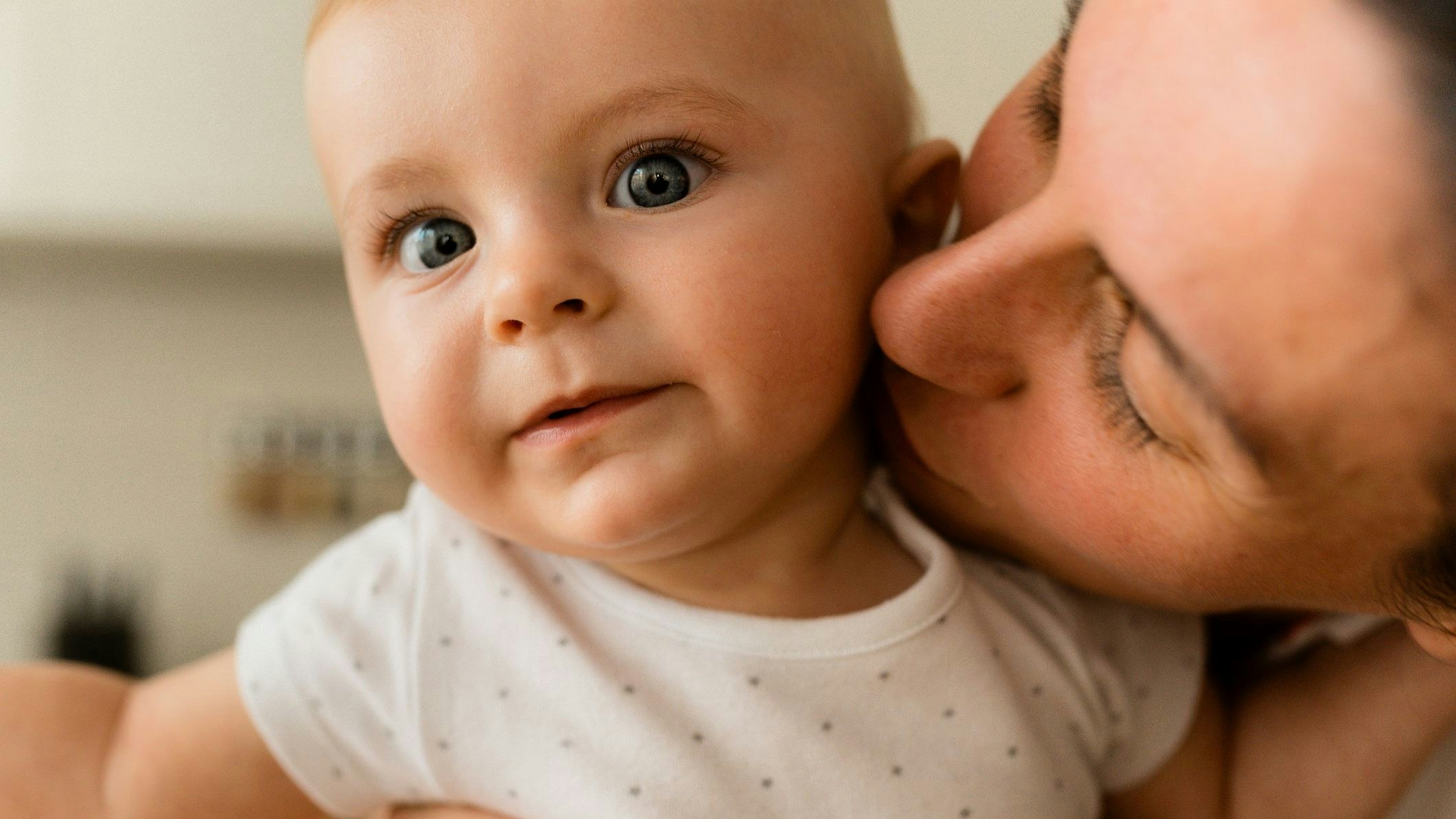 Mother sharing love kissing her little baby boy on the cheek
