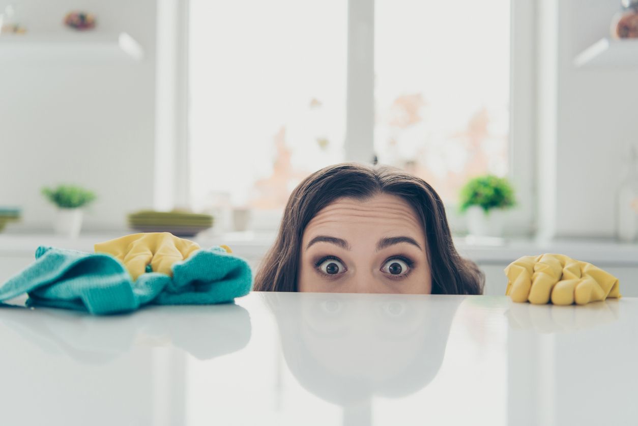 Portrait of her she nice cute lovely beautiful girlish funny shocked wavy-haired house-wife hiding behind shine glossy table in modern light white interior indoors
