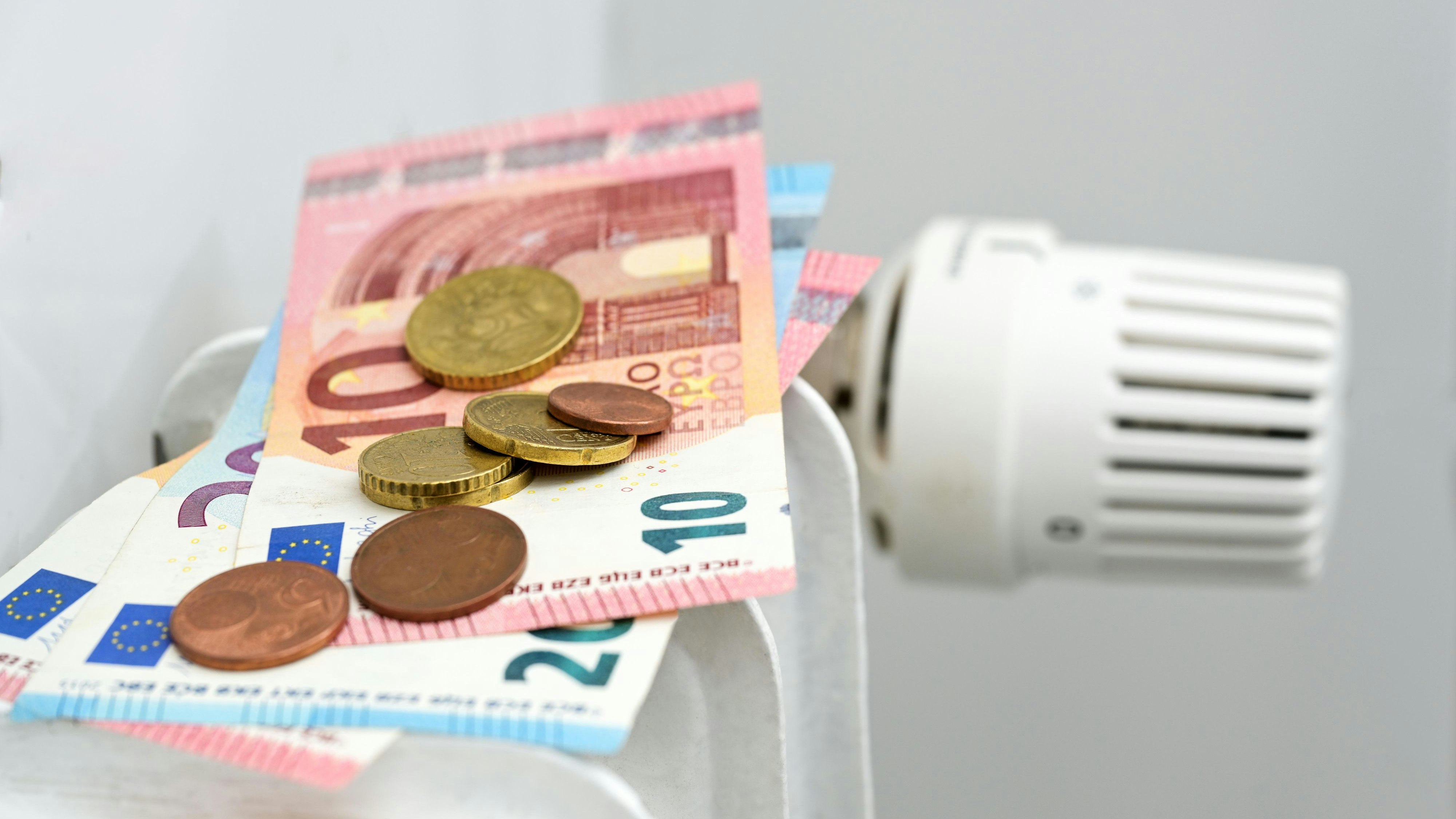 Download von www.picturedesk.com am 14.09.2023 (17:51).  Euro banknotes and coins on a heating radiator, concept for rising energy prices and inflation, copy space, selected focus, narrow depth of field - 20220807_PD17959 - Rechteinfo: Rights Managed (RM)