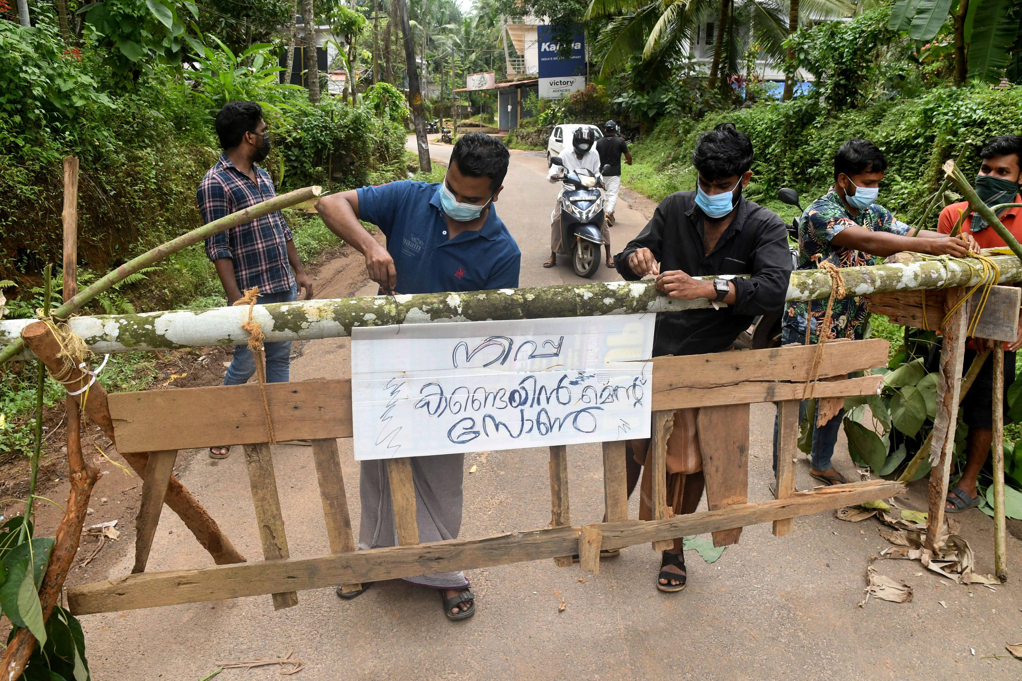 Residents fix a sign reading "Nipah containment zone" on a barricade, put up to block a road after the authorities declared the area a containment zone, to prevent the spread of Nipah virus in Ayanchery village in Kozhikode district, Kerala, India, September 13, 2023. REUTERS/Stringer NO RESALES. NO ARCHIVES