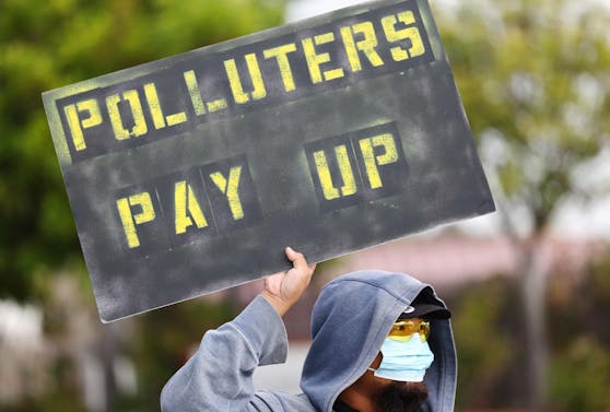 "Verschmutzer zur Kasse bitten" steht auf dem Schild eines Aktivisten bei einem kleinen Protest vor einer Ölraffinerie in L.A.