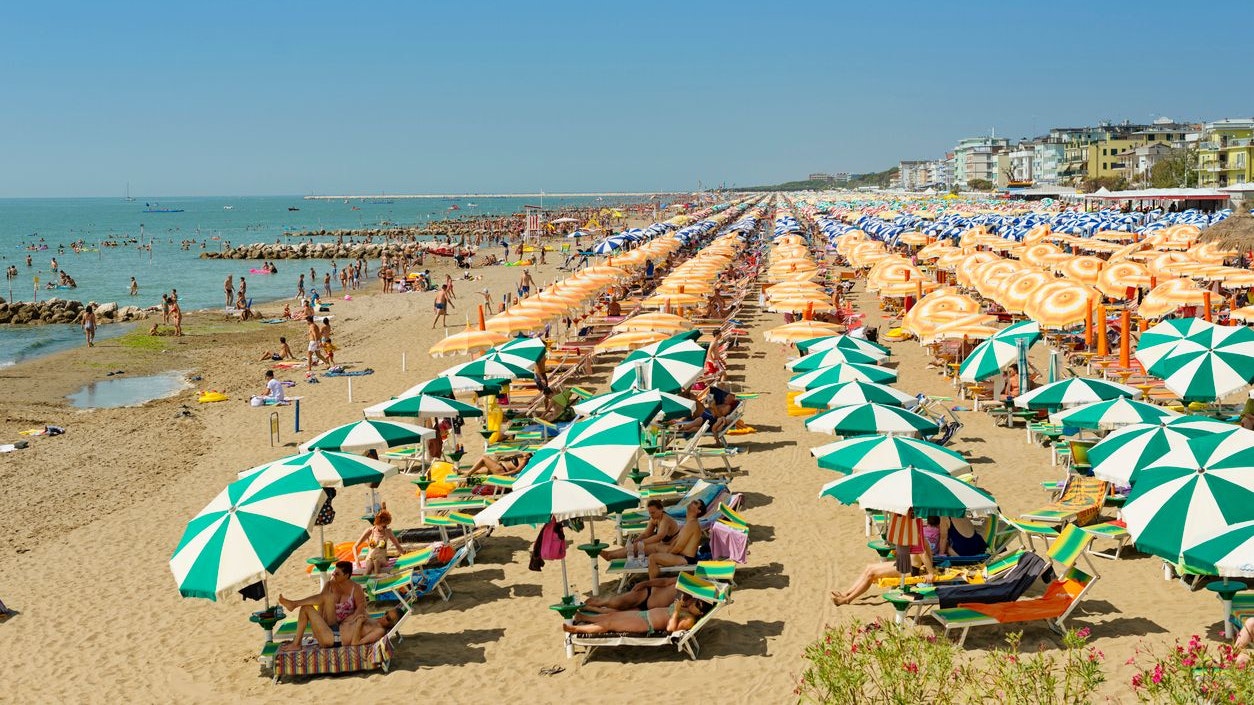 Caorle, Italy - August 7, 2013: Full occupancy beach in Caorle. People lying on beach chairs on the beach and sunbathe. In the background the many hotel can be seen. Caorle a city in the province of Venice with 11,806 inhabitants and a popular destination for beach tourists from Europe and other countries.