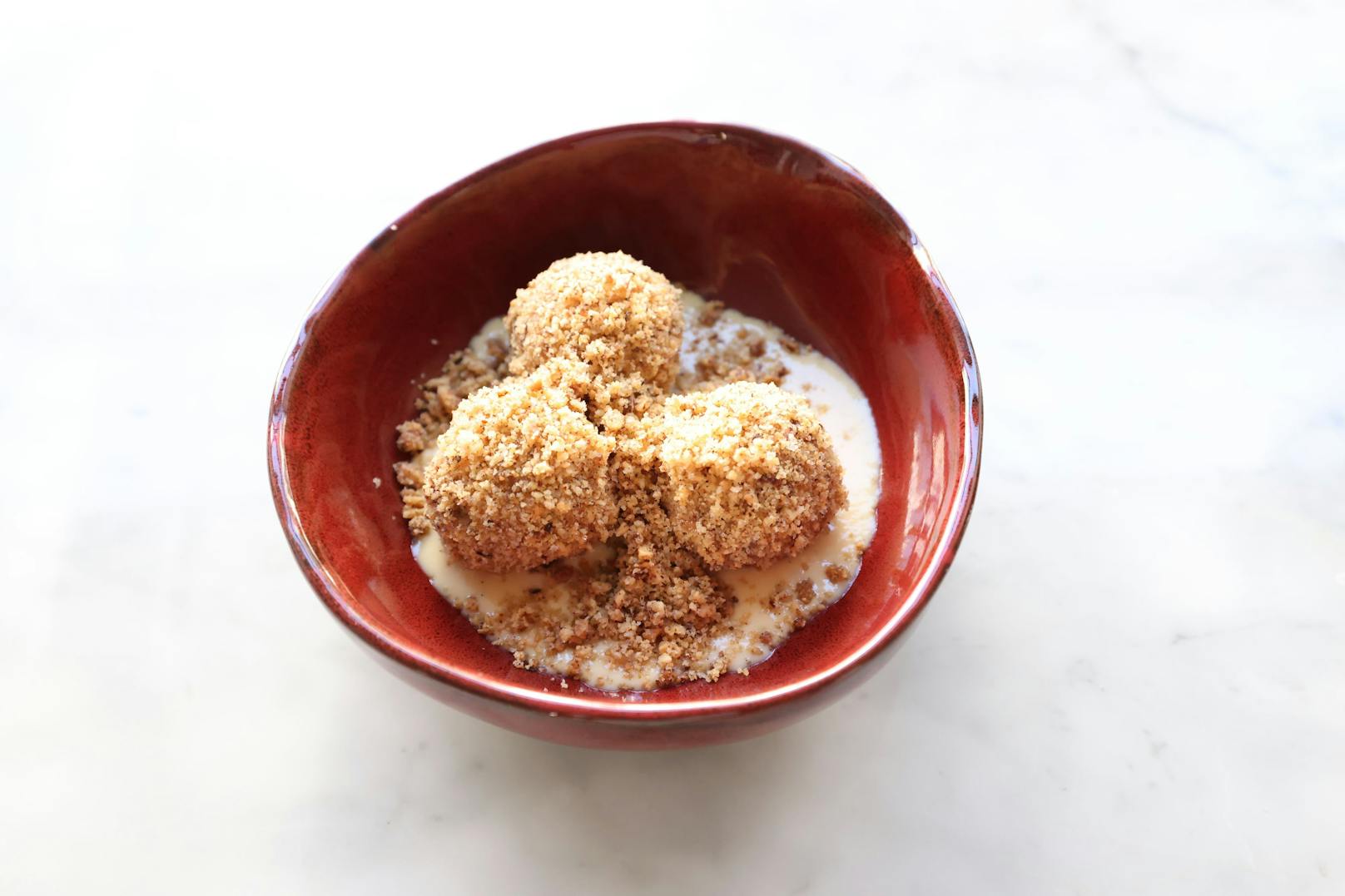 Zum Nachtisch Topfenknödel in getoasteten Haselnussbrösel gerollt, serviert mit Dulche de Leche um 9,90 Euro