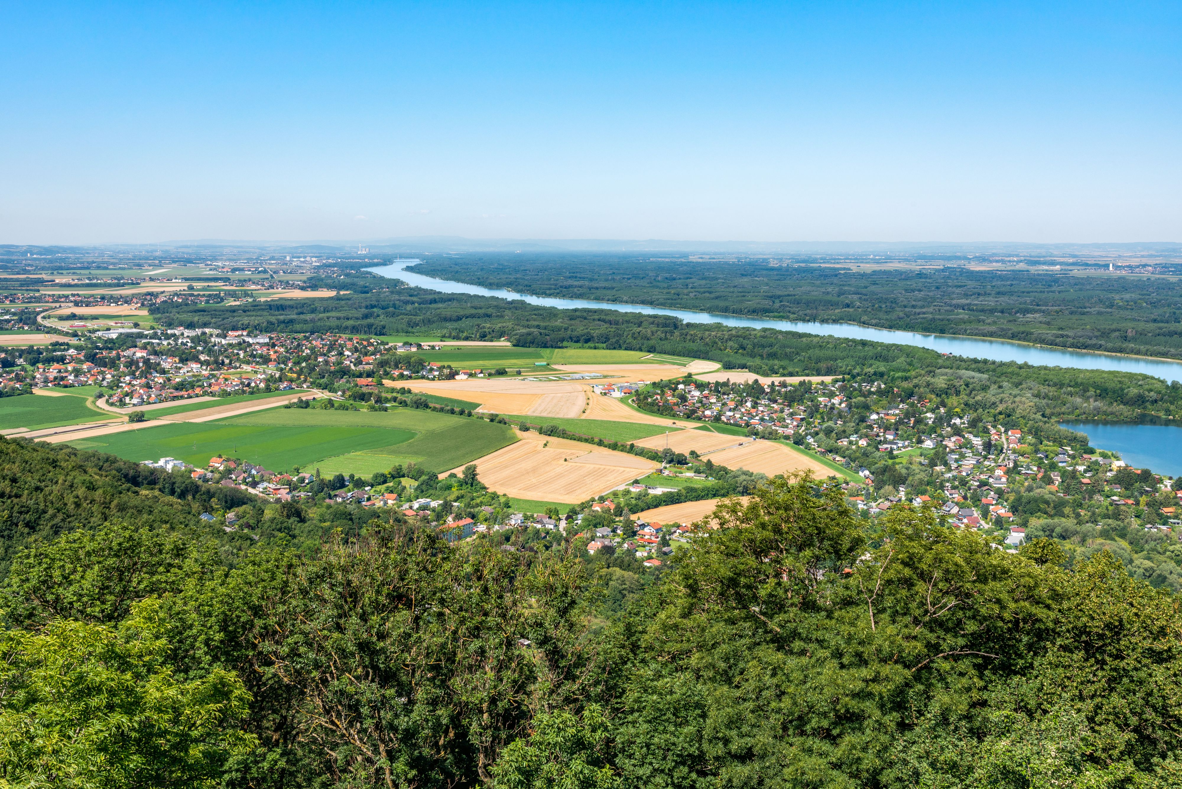 Blick auf das <strong>Tullnerfeld</strong> von der Tempelbergwarte in Altenberg. Knapp unter dem Horizont links des Donauknicks ist <strong>Langenlebarn</strong> samt Fliegerhorst zu sehen. Dahinter sind <strong>Tulln</strong> und das <strong>AKW Zwentendorf</strong> auszumachen. Archivbild, Juli 2020.