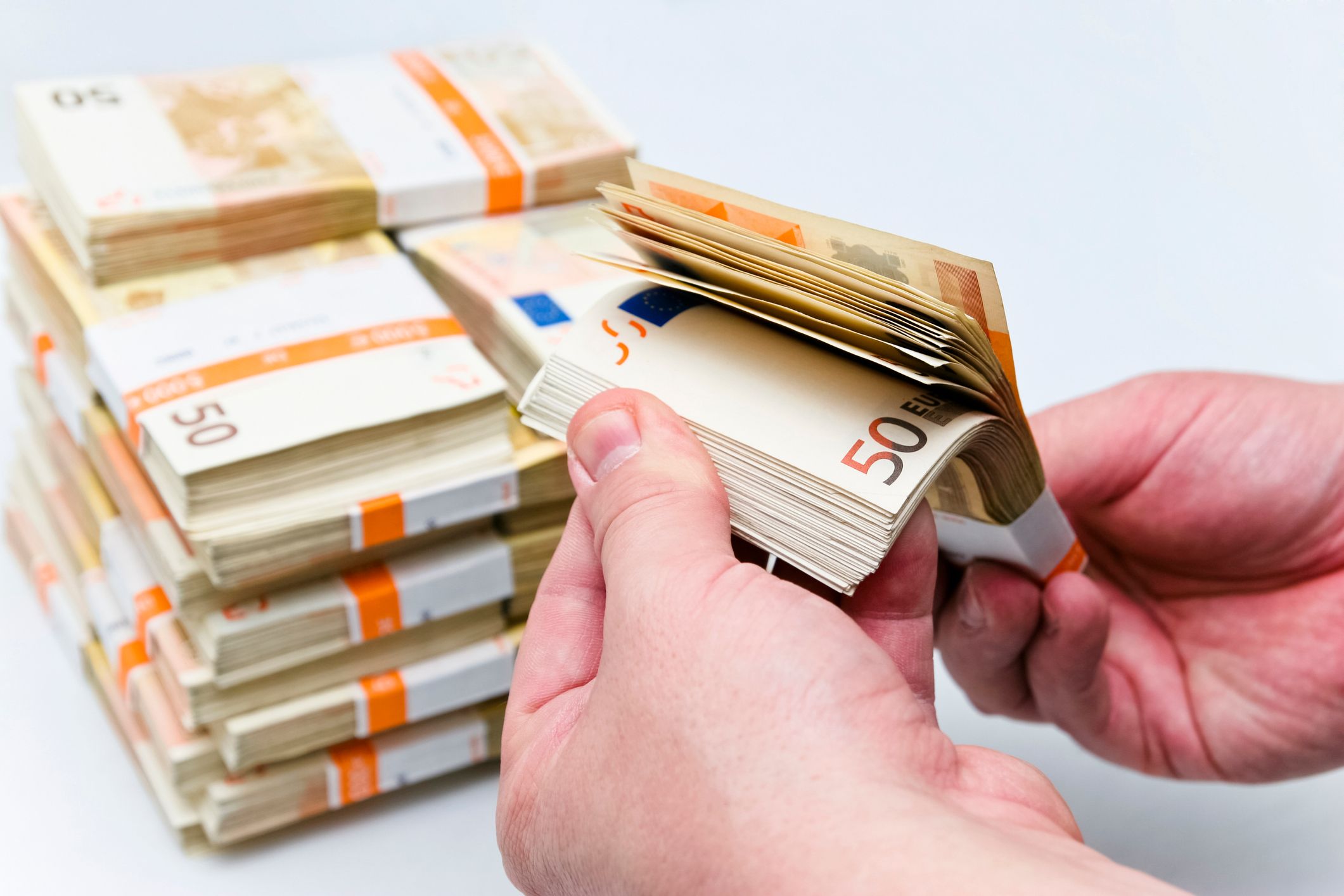 Male hands counting wads of fifty euro bills, a grand total of one hundred thousand euros. This image is part of a series,