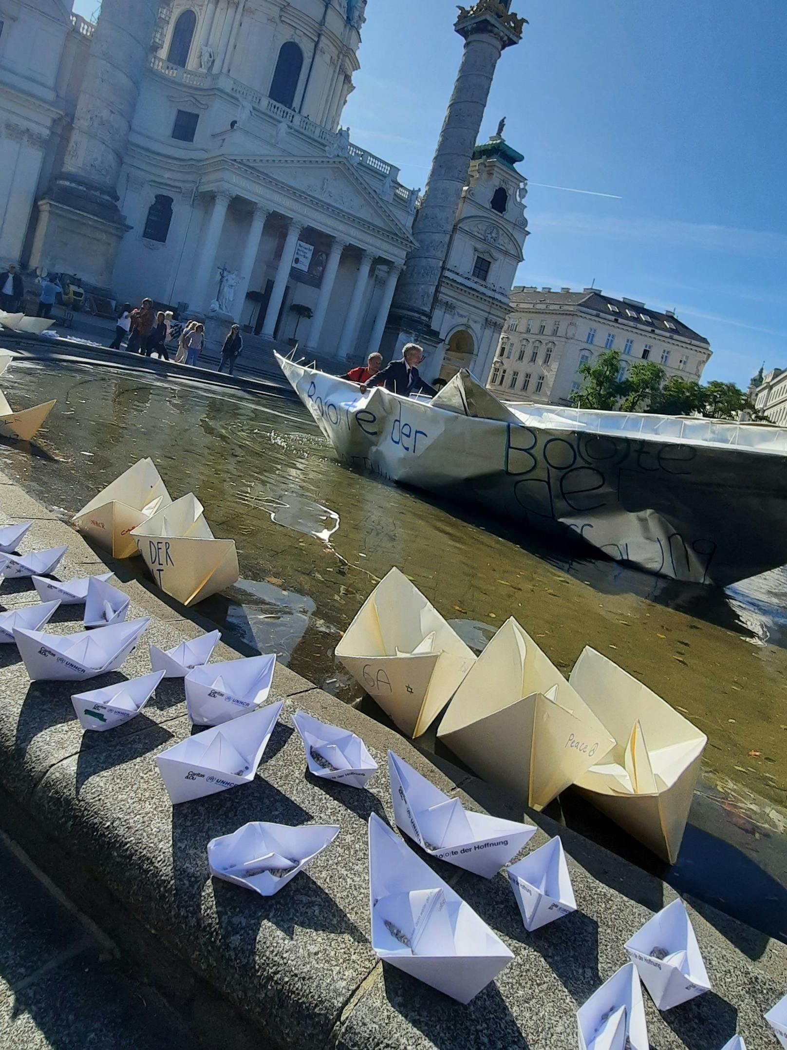Unter Anleitung des Kölner Künstlers <strong>Frank Bölter</strong> bastelten rund 100 Freiwillige am "Langen Tag der Flucht" ein neun Meter langes Papierfaltboot – und setzten es im Brunnen vor der Karlskirche aus.