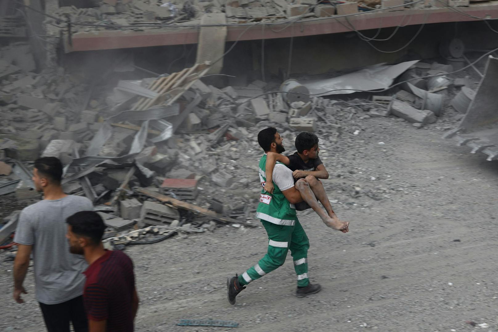 Ein Mitglied des palästinensischen Zivilschutzes rettet einen verwundeten Jungen aus den Trümmern eines Hauses.