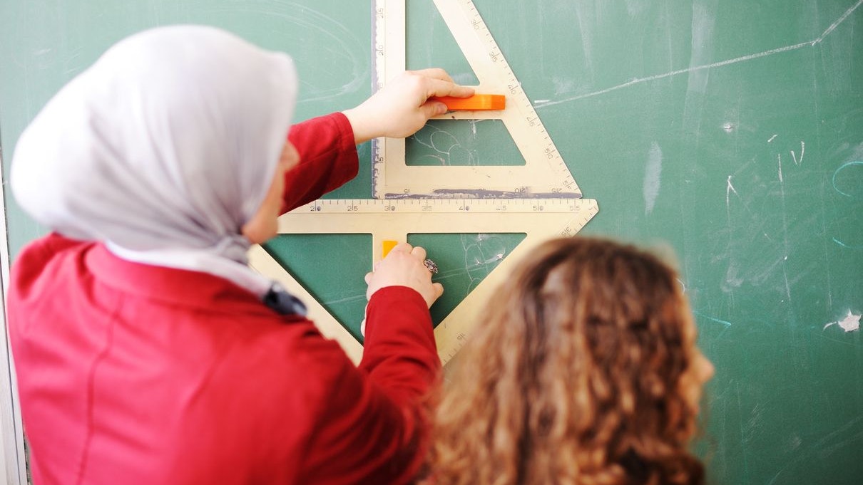 Arabic Muslim teacher showing school girls on the classroom board