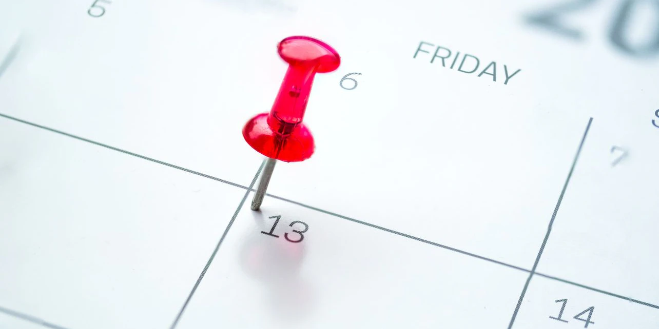 Red push pin on calendar friday the 13th day of the month