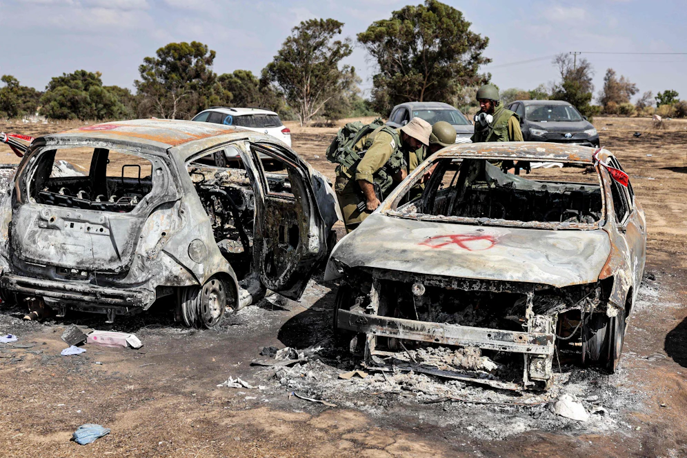Israelische Soldaten durchsuchen ein durch den Hamas-Terror zerstörtes Wrack.