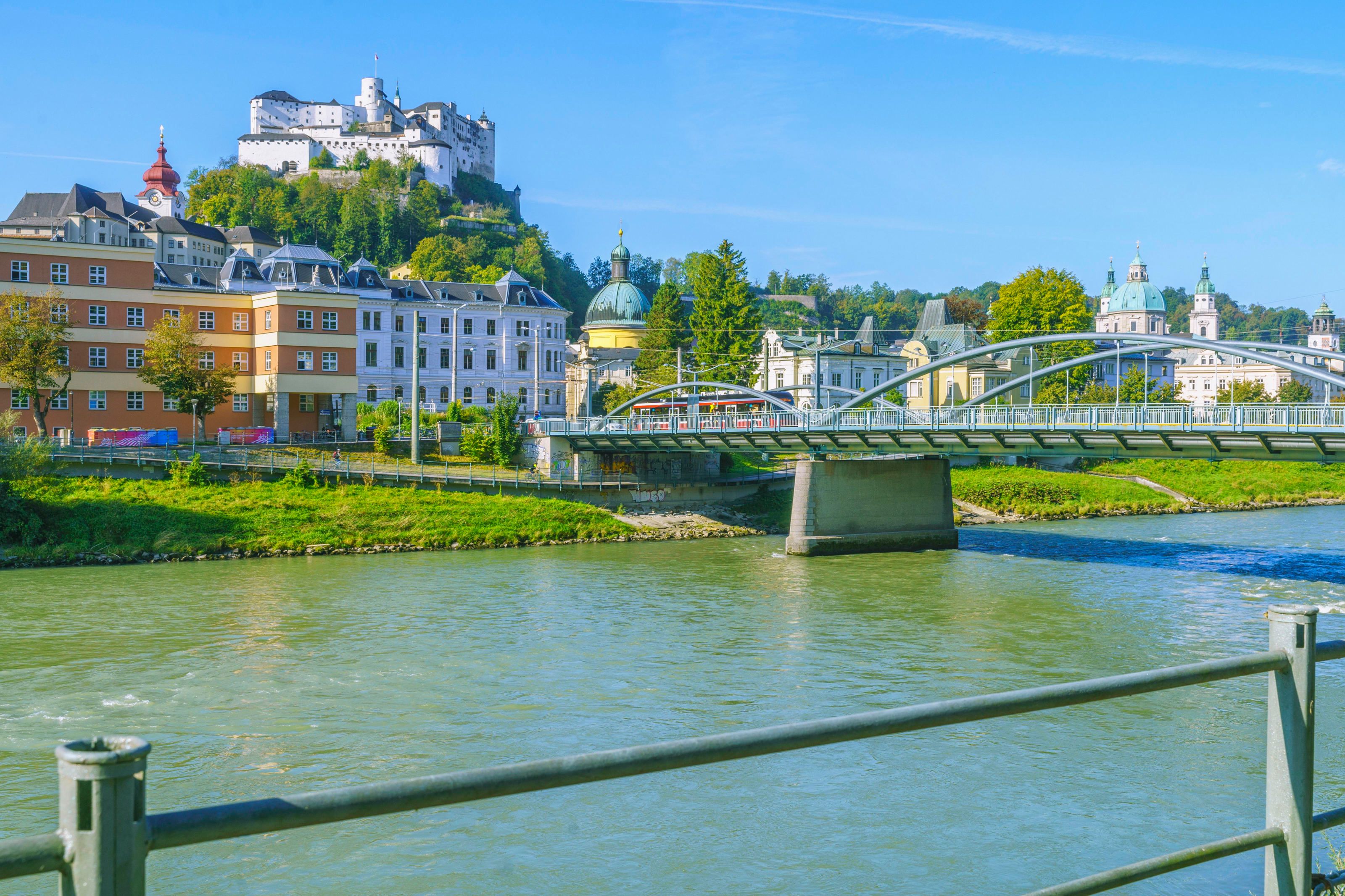Blick über die Karolinenbrücke hinüber zum Rudolfsplatz im Stadtteil Nonntal mit dem Justizgebäude, darüber die Festung Hohensalzburg.